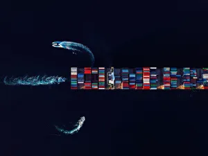 Aerial view of a cargo ship loaded with containers being instructed by two pilot boats Aerial view of a cargo ship loaded with containers being instructed by two pilot boats