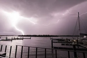 Flashes of bright lightning strikes across the water with boats silhouetted Flashes of bright lightning strikes across the water with boats silhouetted