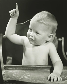 Baby boy (6-12 months) pointing, sitting in high chair, (B&W), portrait Baby boy (6-12 months) pointing, sitting in high chair, (B&W), portrait