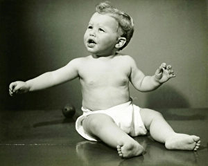 Baby boy (6-12) in nappy sitting on floor, (B&W) Baby boy (6-12) in nappy sitting on floor, (B&W)