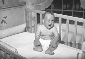 Baby boy (6-9 months) sitting in crib, crying, (B&W) Baby boy (6-9 months) sitting in crib, crying, (B&W)