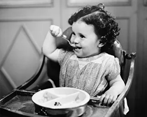 Baby girl (12-18 months) in highchair eating, (B&W) Baby girl (12-18 months) in highchair eating, (B&W)