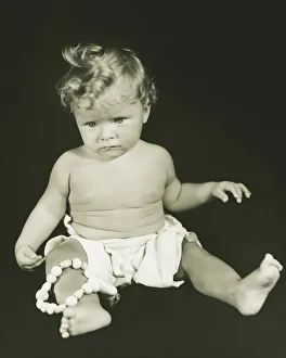 Baby girl (6-12 months) sitting against black background, (B&W), close-up Baby girl (6-12 months) sitting against black background, (B&W), close-up