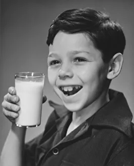 Boy (8-9) holding glass of milk, smiling (B&W), portrait Boy (8-9) holding glass of milk, smiling (B&W), portrait