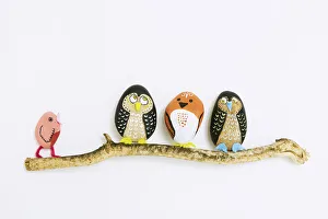 Decorated painted stone birds perching on a branch Decorated painted stone birds perching on a branch