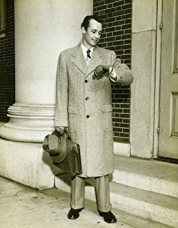 Elegant man checking watch at entrance to building, (B&W) Elegant man checking watch at entrance to building, (B&W)