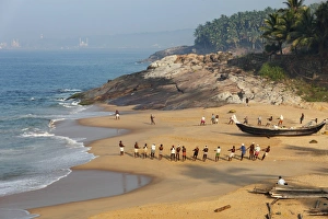 Fishermen pulling in a net, beach south of Kovalam, Vizhinjam in the distance, Malabar Coast, Malabar, Kerala Fishermen pulling in a net, beach south of Kovalam, Vizhinjam in the distance, Malabar Coast, Malabar, Kerala
