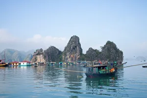 Floating Vietnamese fishing village with rocky coastline Floating Vietnamese fishing village with rocky coastline