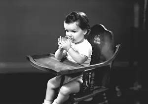 Girl (2-3) sitting in high chair, drinking from glass, (B&W) Girl (2-3) sitting in high chair, drinking from glass, (B&W)