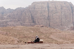 A guard in traditional attire and the splendid view of Wadi Musa from the Urn Tomb, Petra A guard in traditional attire and the splendid view of Wadi Musa from the Urn Tomb, Petra