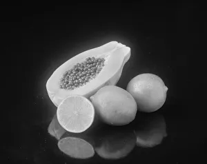 Half cut papaya and lemon on black background Half cut papaya and lemon on black background