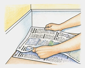 Hands placing layers of newspaper as alternative to underfelt on clean hard floor before laying carpet Hands placing layers of newspaper as alternative to underfelt on clean hard floor before laying carpet