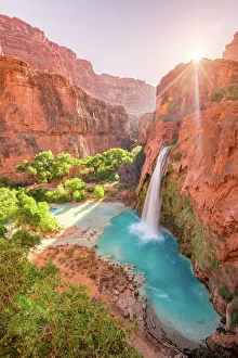 Havasu Falls in Arizona plunges in turquoise waters as the sun rises above the cliffside Havasu Falls in Arizona plunges in turquoise waters as the sun rises above the cliffside