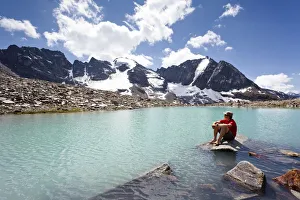 Hiker taking a break at the lake below Mt Tschenglser Hochwand or Croda di Cengles Hiker taking a break at the lake below Mt Tschenglser Hochwand or Croda di Cengles