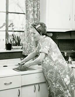 Housewife doing dishes at kitchen sink, (B&W) Housewife doing dishes at kitchen sink, (B&W)