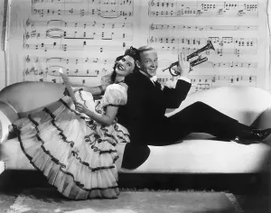 Prints of 1940: American actor and dancer Fred Astaire (1899 -1987) holds a trumpet as he sits back to back with American actor Paulette Goddard (1911 - 1990) Actors And Actress Prints: Fred Astaire and Paulette Goddard in Second Chorus Print