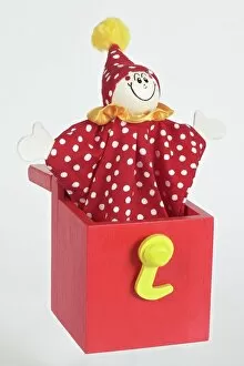 Images Dated 8th November 2005: Jack in a box, smiling clown puppet popping out of red wooden box with arms extended to sides