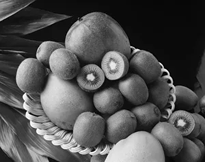 Kiwi fruits and mangos on tray against black background Kiwi fruits and mangos on tray against black background