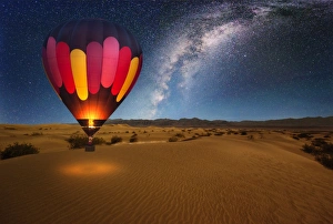 A majestic hot air balloon soars under the stars of the Milky Way, over the desert - Mesquite Dunes of Death Valley A majestic hot air balloon soars under the stars of the Milky Way, over the desert - Mesquite Dunes of Death Valley