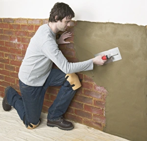 Man applying waterproof render to a wall with a trowel Man applying waterproof render to a wall with a trowel