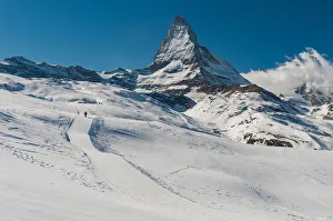 a man walking on a snow trail with Matterhorn background a man walking on a snow trail with Matterhorn background