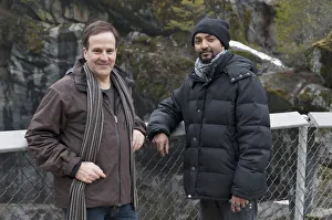 Two Men Standing At A Fenced Lookout Point With Moss Covered Rock In The Background In Two Men Standing At A Fenced Lookout Point With Moss Covered Rock In The Background In