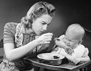 Mother trying to feed unwilling baby (9-12 months), (B&W) Mother trying to feed unwilling baby (9-12 months), (B&W)