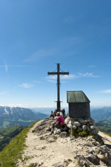 Mountain climber at the summit cross with a small chapel on Geigelstein Mountain, 1808 m Mountain climber at the summit cross with a small chapel on Geigelstein Mountain, 1808 m