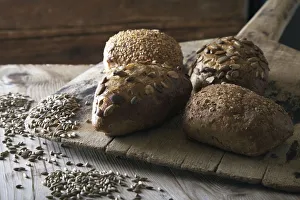 Multigrain bread rolls on old bread slide with rye grains Multigrain bread rolls on old bread slide with rye grains