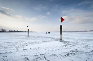 Navigation mark on a frozen Lake Constance with skaters, island auf Reichenau, Konstanz district, Baden-Wuerttemberg Navigation mark on a frozen Lake Constance with skaters, island auf Reichenau, Konstanz district, Baden-Wuerttemberg