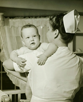 Nurse holding baby boy (6-12 months), (B&W) Nurse holding baby boy (6-12 months), (B&W)