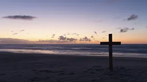 An old cross on sand dune next to the ocean with a calm sunrise - Arniston, South Africa An old cross on sand dune next to the ocean with a calm sunrise - Arniston, South Africa