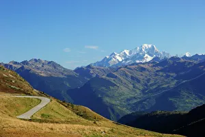 The pass road leading up to Col de la Madeleine, the snow-capped peaks of the Mont Blanc Massif at the back, Alps The pass road leading up to Col de la Madeleine, the snow-capped peaks of the Mont Blanc Massif at the back, Alps