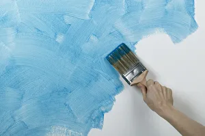 Person painting glaze onto wall with brush Person painting glaze onto wall with brush