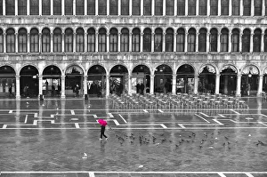 One person with a red umbrella crossing the St Marks Square by a rainy day in winter in One person with a red umbrella crossing the St Marks Square by a rainy day in winter in