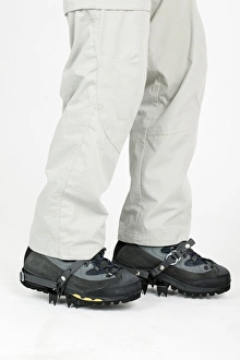 Person wearing boots with crampons, low section Person wearing boots with crampons, low section