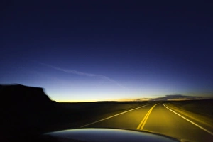 Road past sandstone buttes, lit by headlights, night (blurred motion) Road past sandstone buttes, lit by headlights, night (blurred motion)