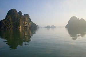 Rocky islands with still water in misty morning Rocky islands with still water in misty morning