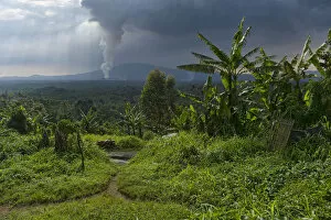 Virunga National Park Collection: Rural dwelling with erupting Nyamuragira Volcano in background, Virunga National Park
