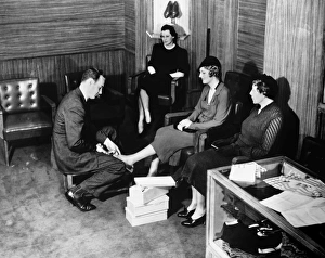 Shop clerk measuring clients foot (B&W), elevated view Shop clerk measuring clients foot (B&W), elevated view
