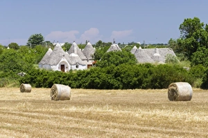 Stubble field, straw bales, Trulli houses, traditional round houses, at the back, near Locorotondo, Valle dItria Stubble field, straw bales, Trulli houses, traditional round houses, at the back, near Locorotondo, Valle dItria
