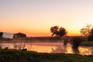 The sun rises over a small dam in the high veld winter landscape near Hartebeespoort, South Africa The sun rises over a small dam in the high veld winter landscape near Hartebeespoort, South Africa