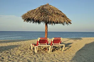Empty sunbeds under a parasol on the beach of Playa Ancon near Trinidad, Cuba, Caribbean Empty sunbeds under a parasol on the beach of Playa Ancon near Trinidad, Cuba, Caribbean