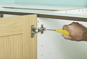 Tightening central screw in a hinge with a screw driver, close up Tightening central screw in a hinge with a screw driver, close up