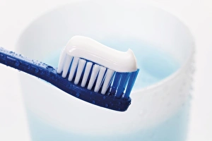 Toothbrush with toothpaste in front of a toothbrush tumbler with mouthwash Toothbrush with toothpaste in front of a toothbrush tumbler with mouthwash