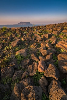 Volcanic rock at Seopjikoji coast with Seongsan background Volcanic rock at Seopjikoji coast with Seongsan background