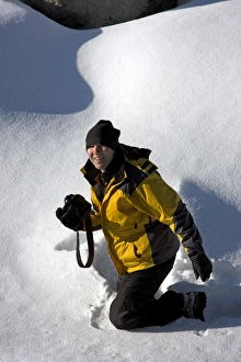 Woman kneeling in the snow holding a camera, Jasper National Park, Alberta, Canada Woman kneeling in the snow holding a camera, Jasper National Park, Alberta, Canada
