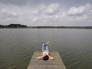 Woman relaxing lying on a wooden pier at a lake, Mecklenburg Lake District, Mecklenburg-Western Pomerania, Germany, Europe Woman relaxing lying on a wooden pier at a lake, Mecklenburg Lake District, Mecklenburg-Western Pomerania, Germany, Europe