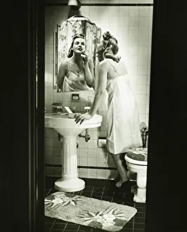 Woman removing make up in front of mirror in bathroom, (B&W) Woman removing make up in front of mirror in bathroom, (B&W)