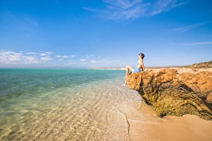 Woman with sarong and straw hat sunbathing at Osprey Bay, Cape Range National Park Woman with sarong and straw hat sunbathing at Osprey Bay, Cape Range National Park